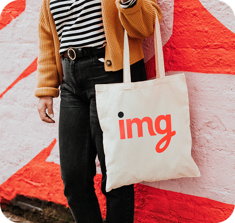 IMG branded tote bag carried against a painted wall